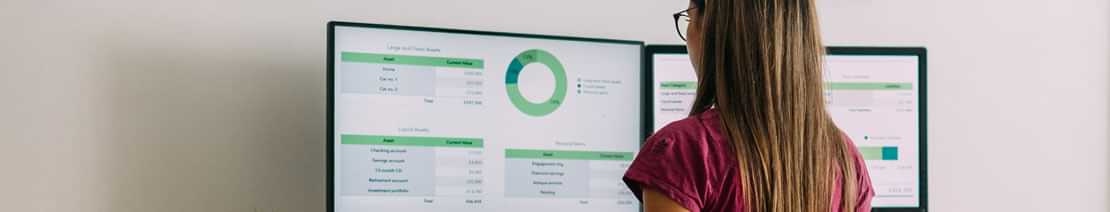woman looking at dual-monitors with dashboard